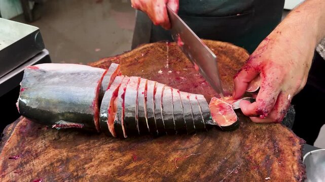 Fresh Fish Steaks Being Cut On Wooden Chopping Block At Traditional Seafood Market