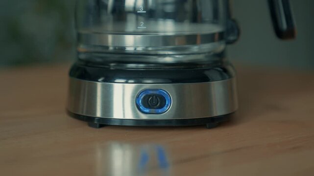 Your finger presses the button on the coffee maker that you can use at home. The technology button lights up.
