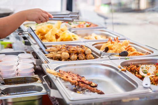 Buffet style food selection with various dishes and a hand serving food