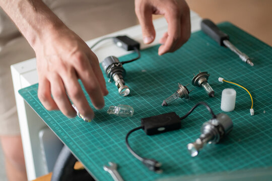 A person is fixing car light lamp parts on a green cutting mat in a home setting in the afternoon