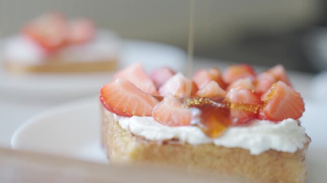 Honey pours over French toast topped with sliced strawberries and yogurt
