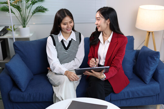 Insurance agent presenting financial planning options to a young woman, advising her during a meeting on a sofa.