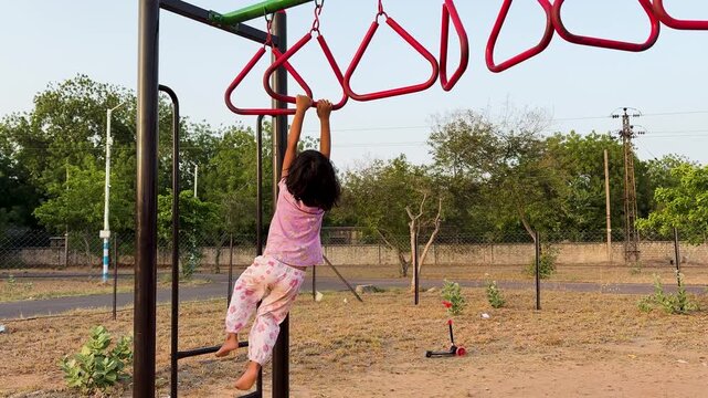 little girl playing on monkey bars enjoying outdoor fitness playground while developing balance and coordination