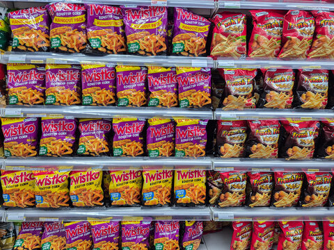 Various brands and logos of potato chip bags on supermarket shelves, displaying snack products in a grocery store aisle.
