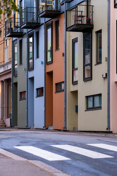 From a crosswalk in Gr&uuml;nerl&oslash;kka, colorful buildings extend along a street, where apartments reveal contemporary architecture through varied facades across Oslo, Norway.