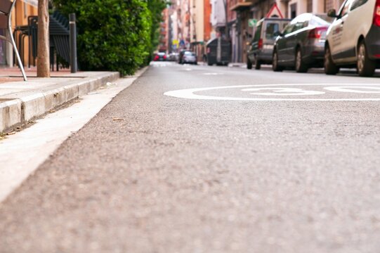 Low angle view of empty asphalt road surface with painted speed limit 30 road-marking on a quiet city street slope in summer
