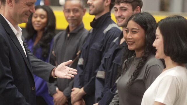 Close-up shot of business partners and industrial engineers shaking hands inside a modern factory. Concept of successful business agreement, international partnership, corporate merger, and B2B manufa