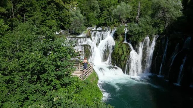 Drone View of Woman Admiring Martin Brod Waterfalls in Una National Park, Bosnia and Herzegovina Surrounded by Nature