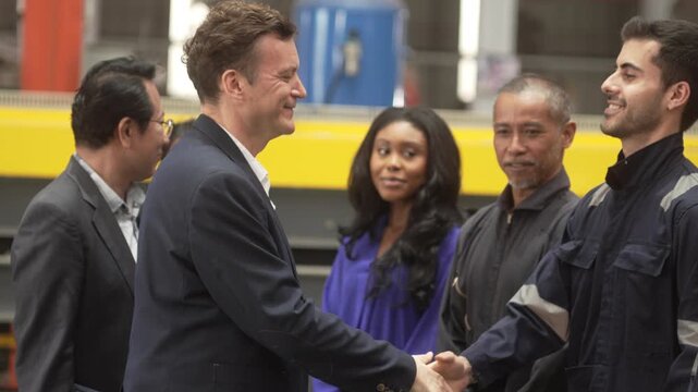 Close-up shot of business partners and industrial engineers shaking hands inside a modern factory. Concept of successful business agreement, international partnership, corporate merger, and B2B manufa