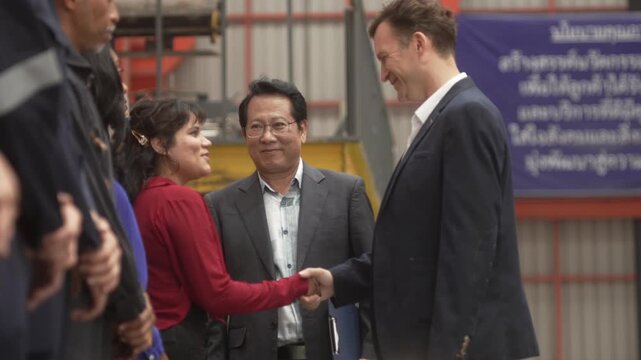 Close-up shot of business partners and industrial engineers shaking hands inside a modern factory. Concept of successful business agreement, international partnership, corporate merger, and B2B manufa