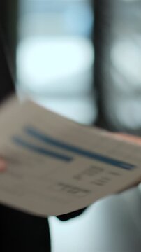 Vertical video Close up woman is opening envelope with Payment notification letter while standing in front of mailboxes in her apartment building. Mail shipping concept.