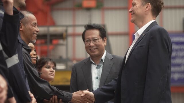 Close-up shot of business partners and industrial engineers shaking hands inside a modern factory. Concept of successful business agreement, international partnership, corporate merger, and B2B manufa