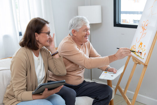 An elderly couple enjoys painting at home
