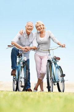 Love, portrait or elderly couple in park with bicycle, bonding or happy moment in weekend activity. Wellness, space or senior people with cycling, romantic relationship or connection in outdoor hobby
