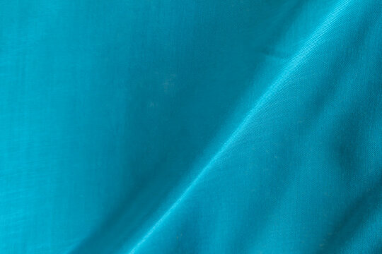 Bright turquoise fabric texture with gentle folds for creative backdrops.