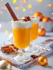 Hot Christmas drink. Egg punch with cinnamon in a glass on a wooden tray. © SG- design