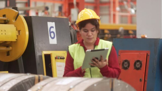 Asian factory executive in suit and female safety engineer reviewing production data on a digital tablet in a heavy machinery plant. Concept of smart factory, digital supply chain management, and indu