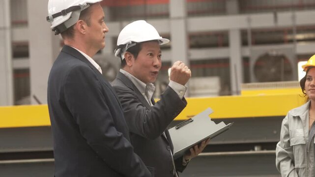 Multi-ethnic group of corporate leaders and factory technicians celebrating a successful deal in a manufacturing plant. Perfect for annual corporate reports, international trade commercials, and ESG s