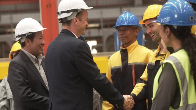 Multi-ethnic group of corporate leaders and factory technicians celebrating a successful deal in a manufacturing plant. Perfect for annual corporate reports, international trade commercials, and ESG s
