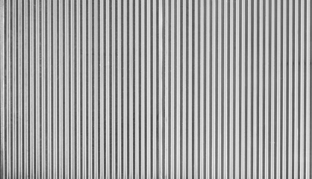 Monochrome gray corrugated metal surface texture background featuring zinc iron panels and steel roller shutter lines perfect as abstract backdrop for commercial graphic design.