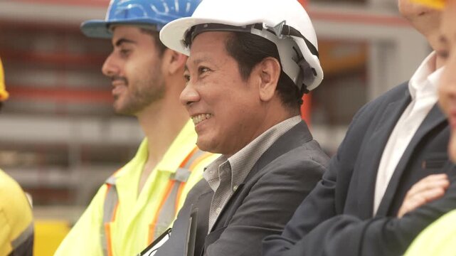 Multi-ethnic group of corporate leaders and factory technicians celebrating a successful deal in a manufacturing plant. Perfect for annual corporate reports, international trade commercials, and ESG s
