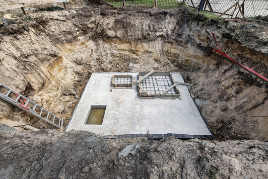 Workers are placing metal rebar in position to reinforce the concrete before it is poured into the foundation at the construction location