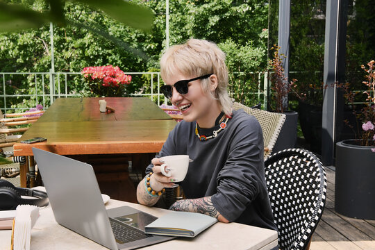 Charming young non binary person enjoying a blissful moment in a cozy outdoor cafe.