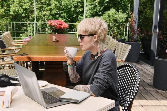 Bright moments in a cozy cafe with a non binary individual enjoying a warm drink and laptop work