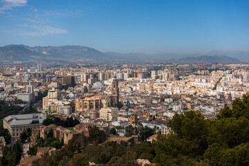 Naklejka premium Expansive view of Málaga, Spain, featuring the Málaga Cathedral prominently in the center. The Alcazaba, a notable Moorish fortress, is visible with its distinct stone walls in the foreground