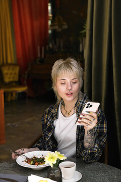 Young beautiful non binary person enjoys a cozy meal in a vibrant cafe atmosphere.