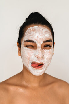 A woman wearing a face mask while making funny faces at home. Skincare