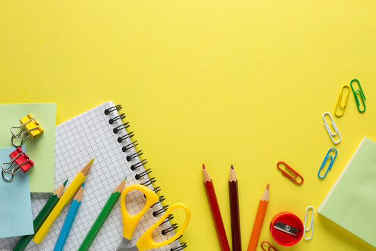 School supplies, colored pencils, notebook on yellow  table. Back to school concept. Flat lay.