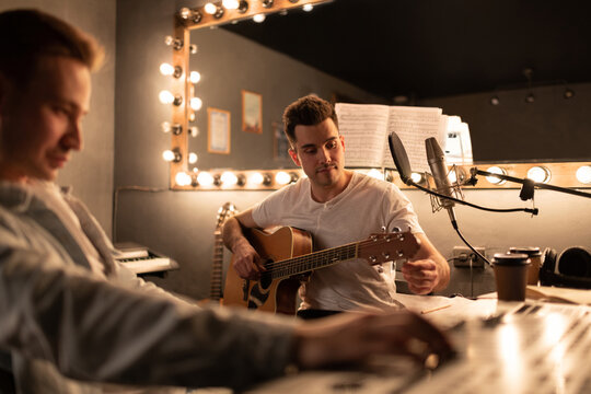 Male guitarist tuning instrument near sound director. 
