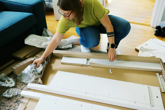 woman in her living room at home assembling furniture