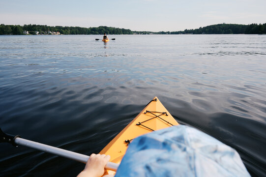 pov of child in kayak on lake holding oar in her hand