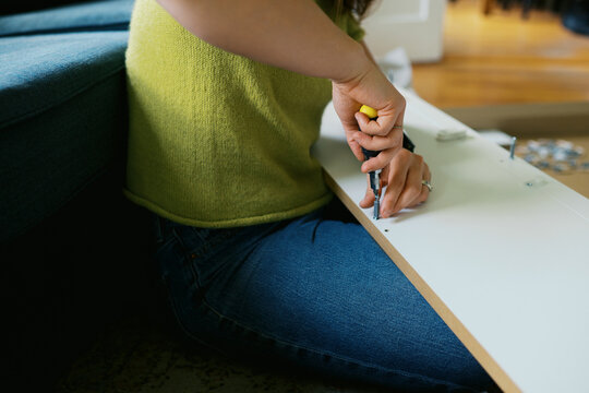 woman in her living room at home assembling furniture