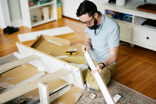 man in his living room at home assembling furniture