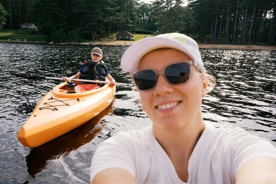 selfie of mom and son on lake in summer in orange kayaks
