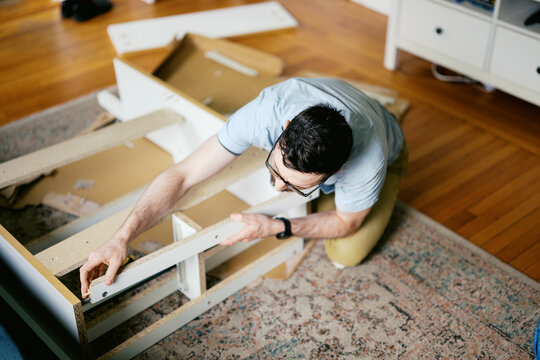 man in his living room at home assembling furniture