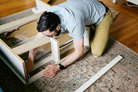man in his living room at home assembling furniture