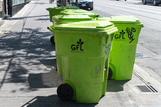 grungy GFL (Green For Life Environmental) recycling bins on a sidewalk in Toronto
