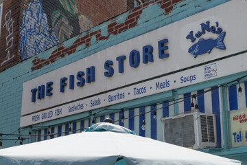 Obraz premium exterior building facade and sign of The Fish Store & YuNes' Sandwiches located at 657 College St, Toronto