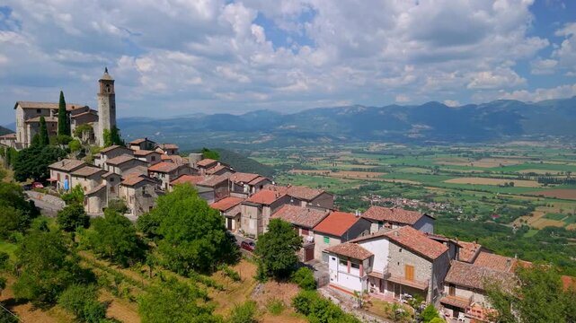 Greccio Italy 4K Drone. Aerial overflight of hilltop borgo on ridge to valley. One of the most beautiful medieval villages historic town with bell tower scenic b-roll cinematic video asset, hidden gem