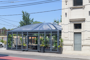 Obraz premium glass-enclosed rear patio / garden dining and detail of heritage Bank of Nova Scotia building - now DaNico, a restaurant, located at northeast corner of Bathurst St and College St, Toronto 