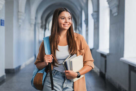 Portrait of schoolgirl with books, notebooks and backpack in modern school hallway, learning, education, youth and academic success concept