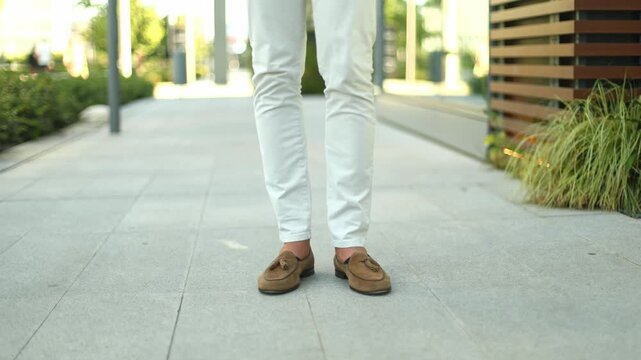 Stylish man in loafers walking on city sidewalk
