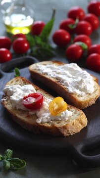 Close-up vertical video of a hand putting red and yellow cherry tomatoes on a toasted Italian bread, or bruschetta, with creamy stracciatella cheese. Rustic Mediterranean appetizer, homemade Italian f
