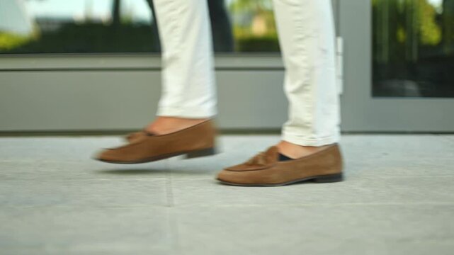 Stylish man in loafers walking on urban sidewalk