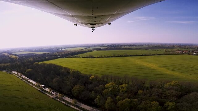 Zeppelin fliegt tief &uuml;ber Felder, Bahngleise und Wald in Bayern