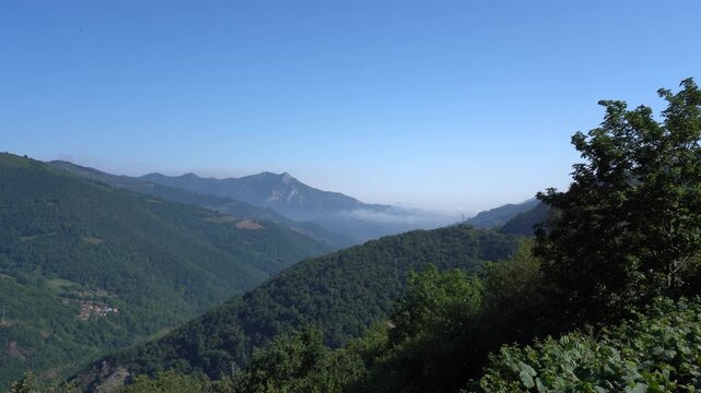 Paisaje monta&ntilde;oso de Asturias con verdes laderas, cumbres, valles y naturaleza exuberante bajo un cielo azul del norte de Espa&ntilde;a.